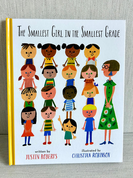 Book cover of ‘The Smallest Girl in the Smallest Grade’ by Justin Roberts and Christian Robinson, featuring illustrated children and a teacher. Part of the Courage Collection from Wonder & Wisdom Books™.