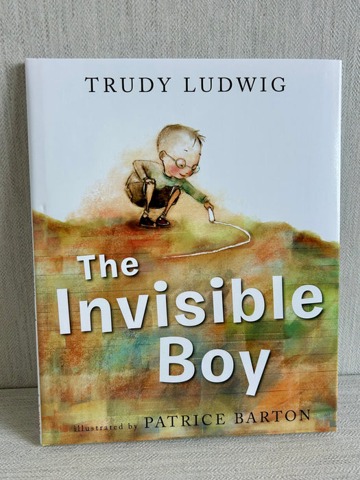 Book cover of “The Invisible Boy” by Trudy Ludwig, illustrated by Patrice Barton, showing a young boy crouched with a piece of chalk on a watercolor-style background.